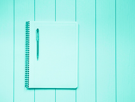 An open notebook and pen sitting on a table. 