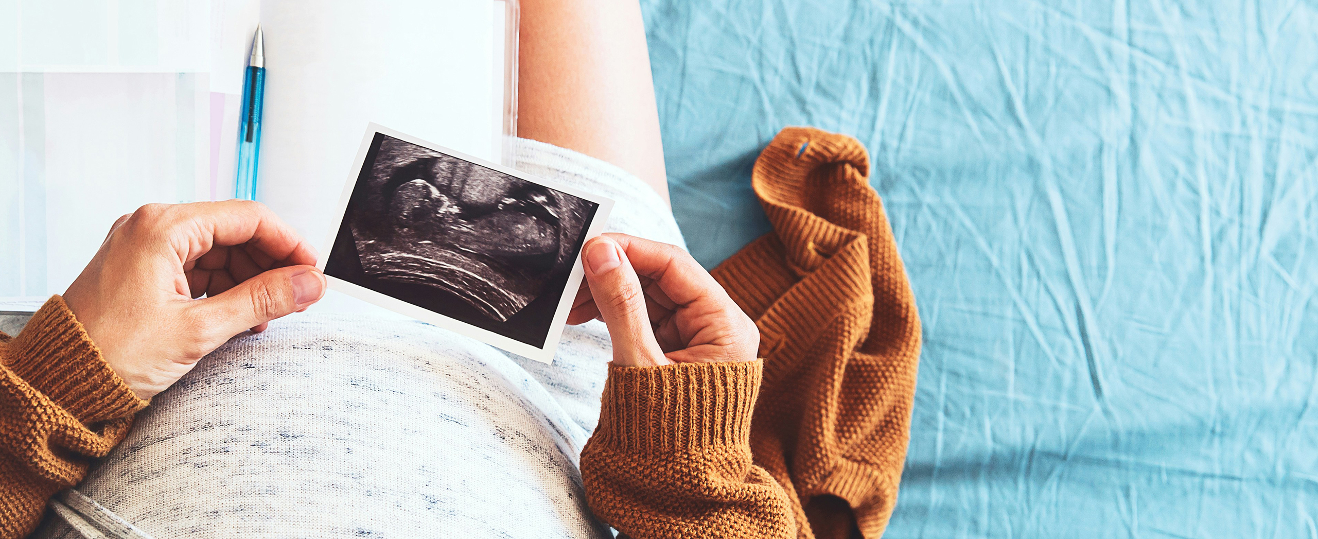 An aerial view of a pregnant woman looking at a photo of an ultrasound.