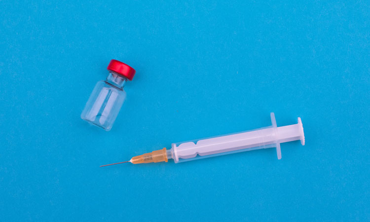 Needle and vial on a blue surface