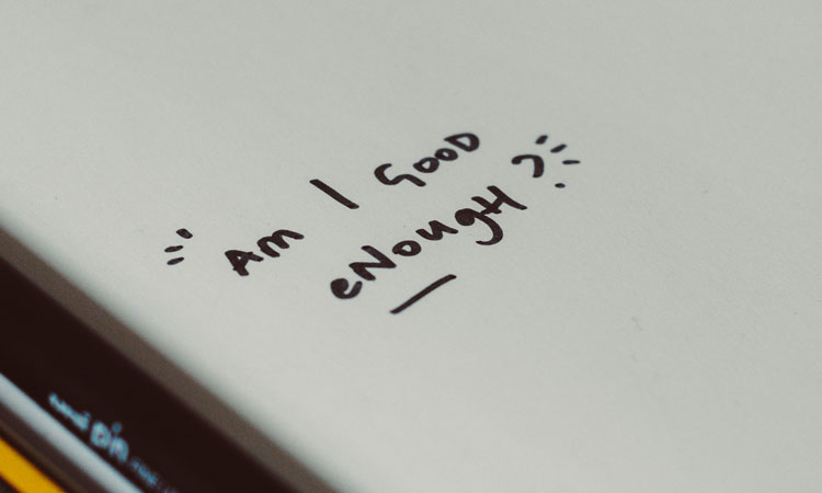The words "Am I good enough?" written on a white surface