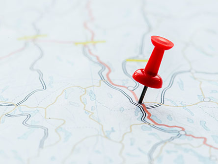 A push pin stuck in a map. 