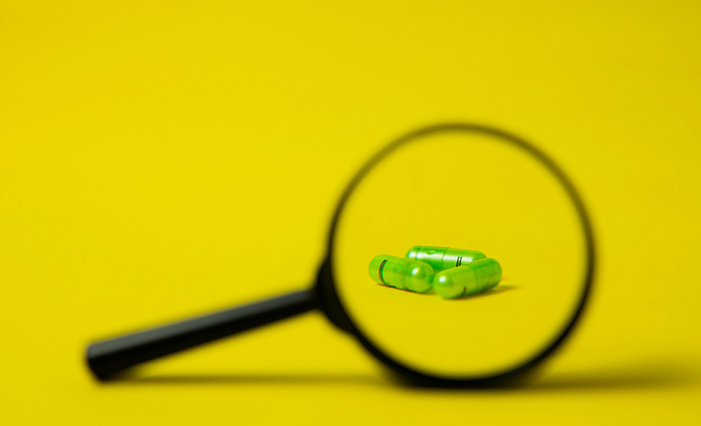 Magnifying glass in front of three pills
