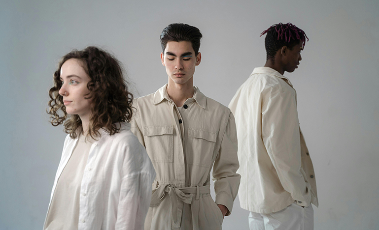 Three Gen Z professionals standing in a plain room looking in different directions.