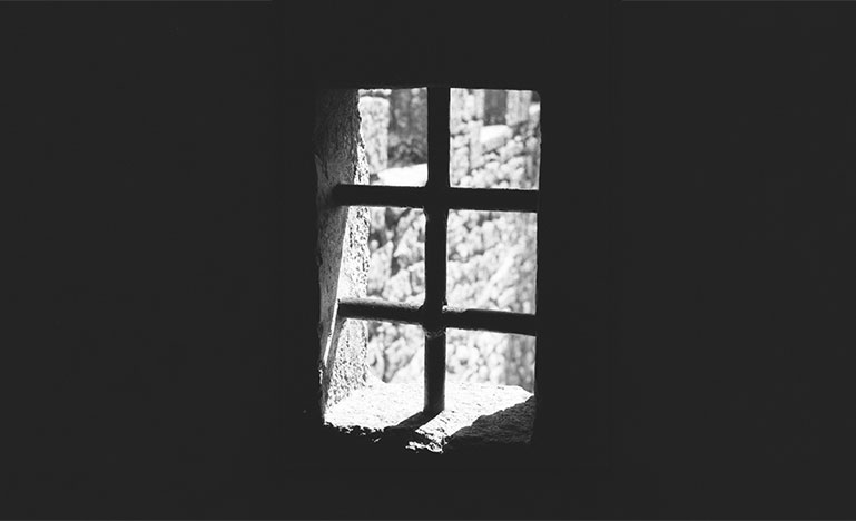 Light shining through the bars of a prison window.