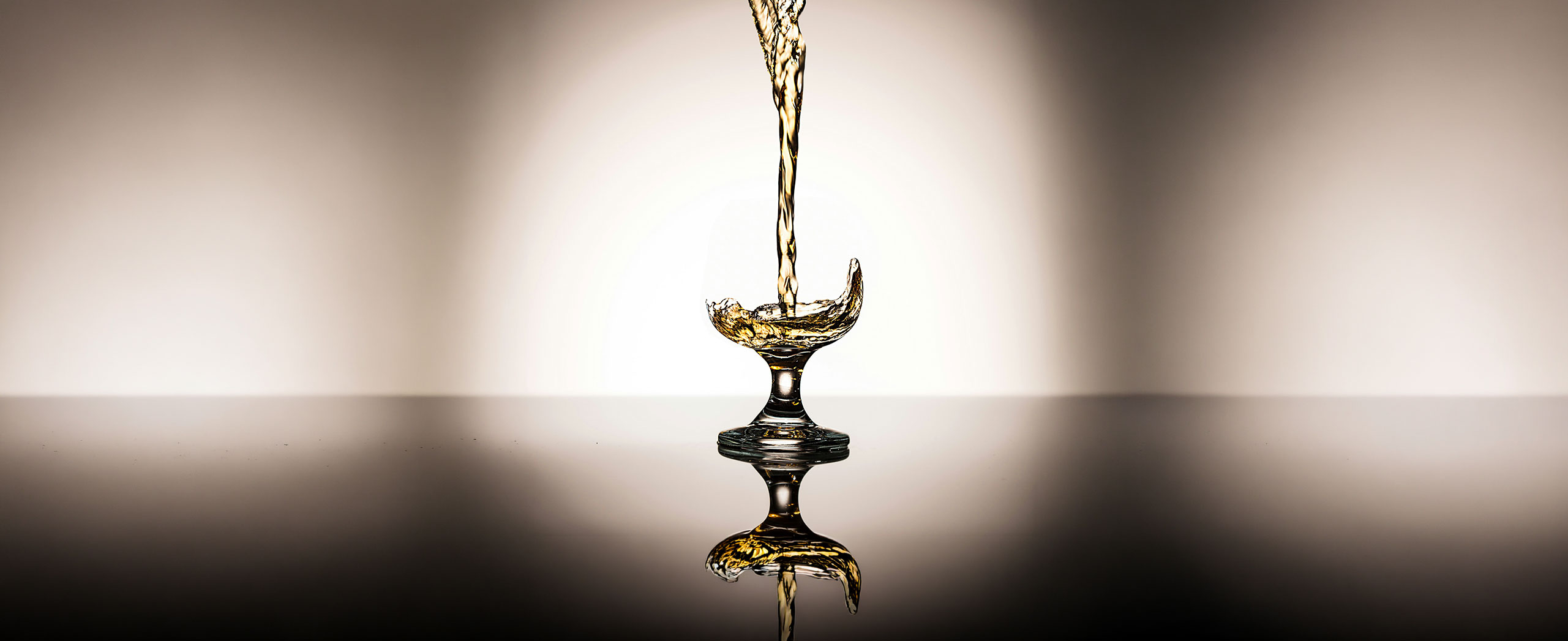 Golden liquid pouring into a glass goblet.