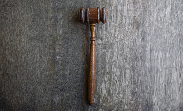 A wood gavel on a grey desk.