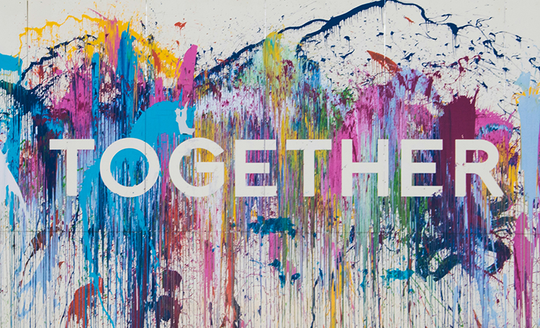 An abstract collage of brightly coloured paint splotches with "Together" stenciled into it.