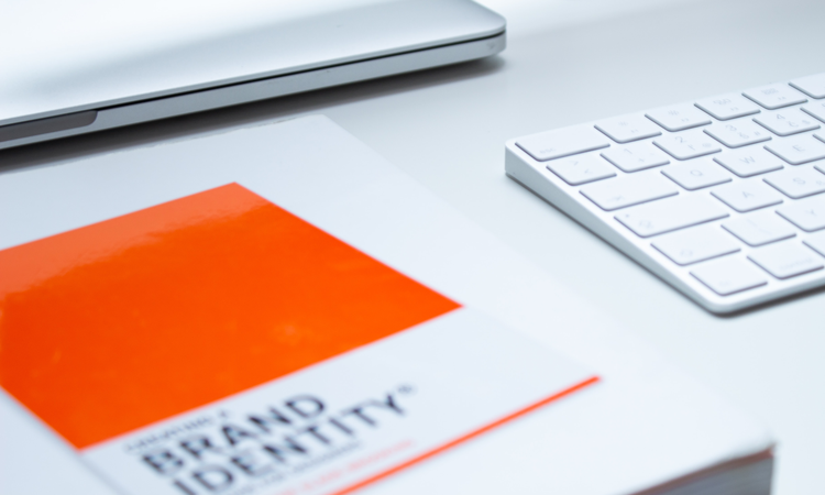 Orange notebook with the words "brand identity" printed on it