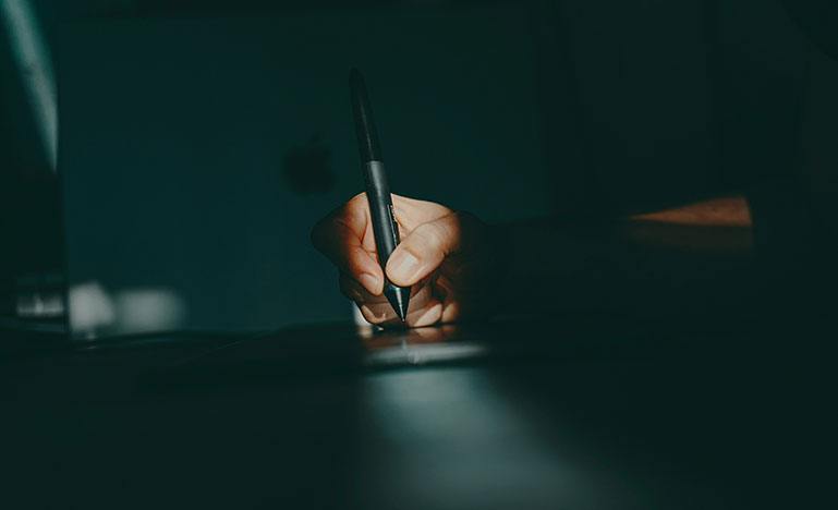 Close up of a hand holding a pen, starting to write.
