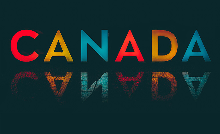 A bright multi-coloured Canada sign on a dark background.