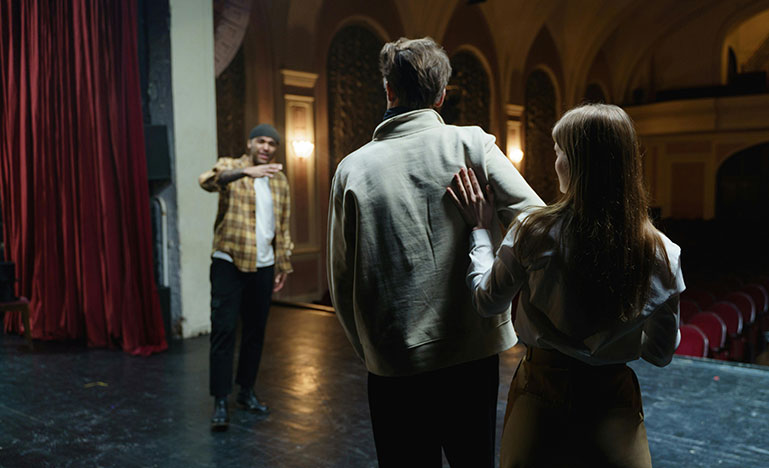 Three improv actors playing out a scene on stage.