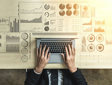 An aerial view of a person at a laptop surrounded by data charts. 