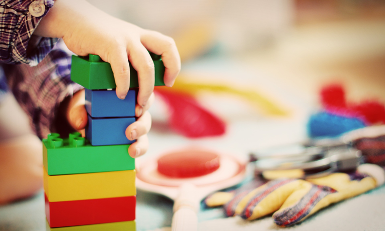 Child's hands building a brightly colour block tower