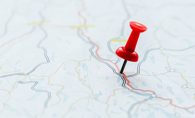A push pin stuck in a map. 