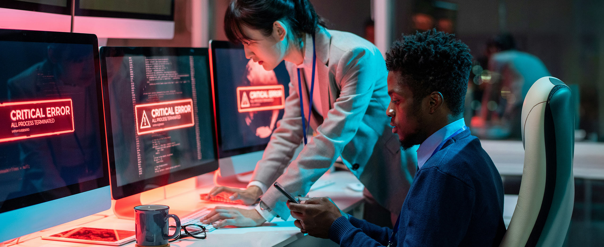 Two IT professionals looking at a set computer screens that have "CRITICAL ERROR" warnings.