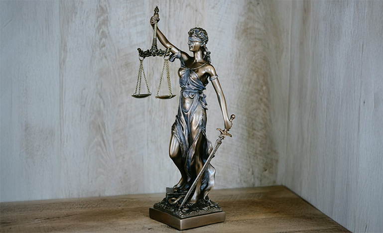A small statue of Themis, the goddess of justice, sitting on a desk.